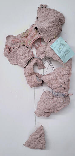 20”x12”, Paper pulp sewn together with thread and a sewn-on notecard with pen scribbles, additional color pencil drawings on the paper, hung with a thumb tack, 2024